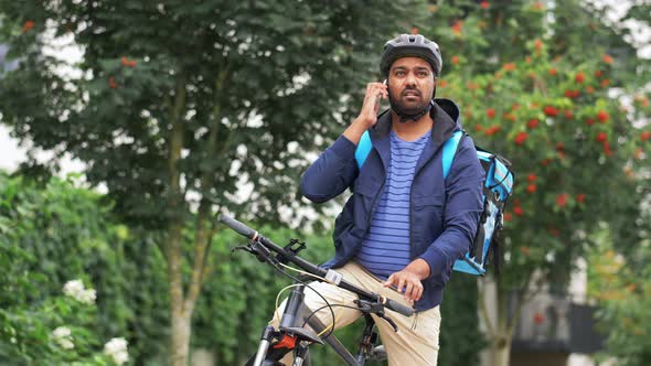 Delivery Man with Bag and Bicycle Calling on Phone alt