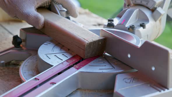 Carpenter Sets Mitre Saw Angle 30 Degrees and Cuts Wooden Workpiece Diagonally alt