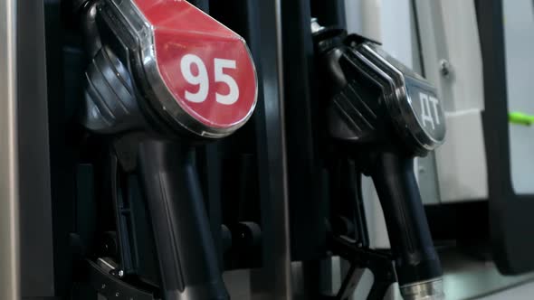 the Hand Holds the Filling Gun at the Gas Station alt