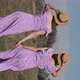 Vertical Young Twins Sisters in Summer Dresses Walks Green Field Holding Hands - VideoHive Item for Sale