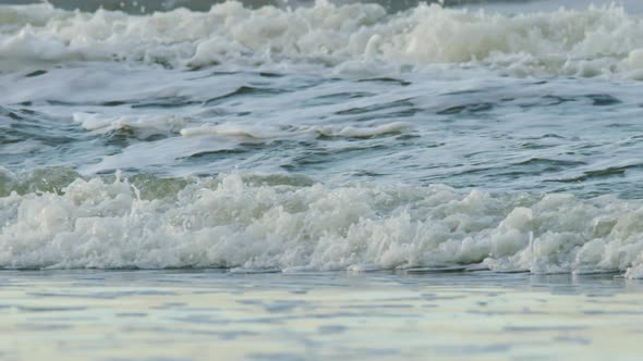 Tropical sea waves rolling and crashing near sandy beach making sounds and foam alt