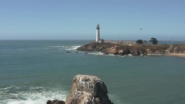 Aerial of Pigeon Point Lighthouse flying over rocks on Pacific Coast Highway near Half Moon Bay on C alt