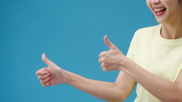 Young woman hand showing thumb up sign with fingers isolated over blue background in studio.