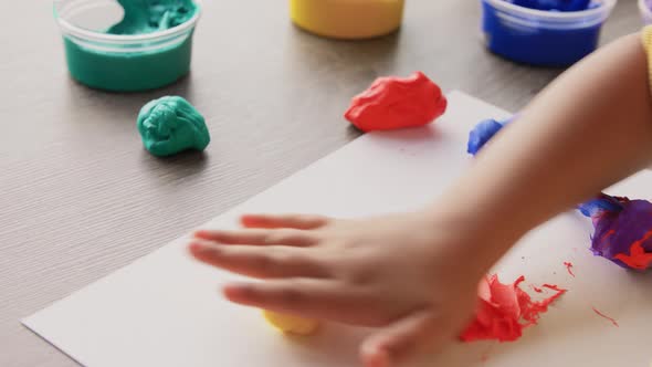 Little Girl Rolling Yellow Modeling Clay at Home alt