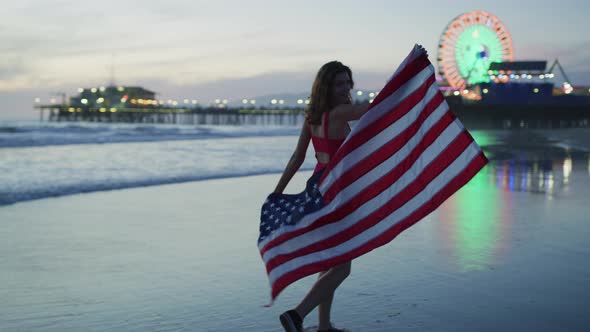 Evening walk on Santa Monica beach, while holding the US flag alt