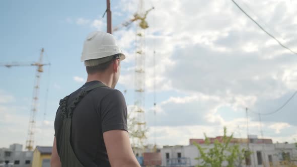 A Builder in a Helmet Is Walking and Inspecting the Construction Site. alt