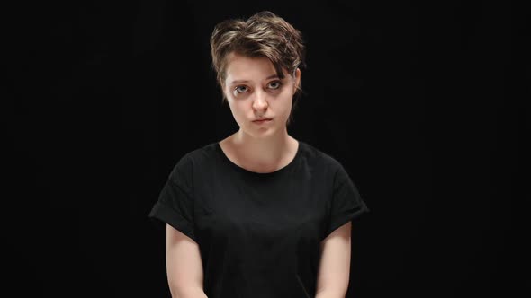 Middle Shot Portrait of Sad Humiliated Young Woman Posing at Black Background alt