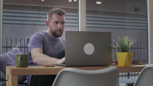 Man with a Beard Uses a Laptop