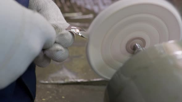 Close Up at the Hands of Worker Burnishing the Finished Silver Spoon with a Machinetool alt