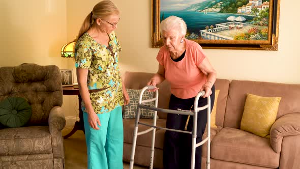 Closeup of home healthcare nurse helps elderly woman get up from couch and use a walker. alt