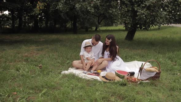 Cheerful Caucasian Mum, Dad and Their Child Have Fun Together and Smiles in the Garden