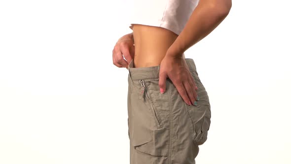 Slim Girl in Big Trousers, Showing Her Lose Weight, on White alt