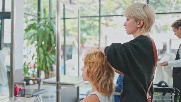 Hairstylist giving advise for hairdo, haircut and styles for Caucasian young woman in beauty salon. alt