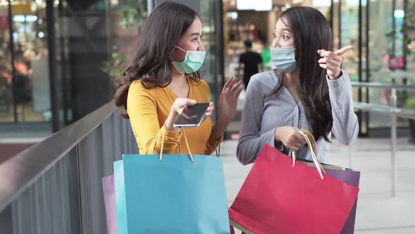 Asian woman wearing face mask. Happy woman with shopping bags alt