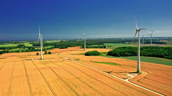 Aerial view of wind turbines and golden field near highway. alt