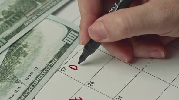 Female Hand Marking the Day in Calendar By Writing DAY DEBT As a Reminder Using a Red Marker alt