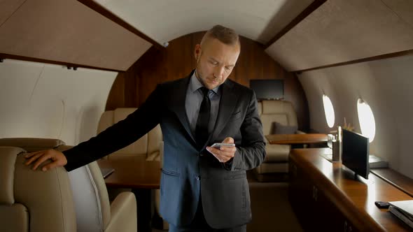 Attractive Entrepreneur with Smartphone Inside of Private Jet alt