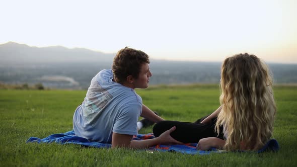 Slow Motion shot of cute couple laying on a blanket and having a picnic on the grass. alt