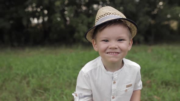 Cute Boy in Hat Waving at Camera.