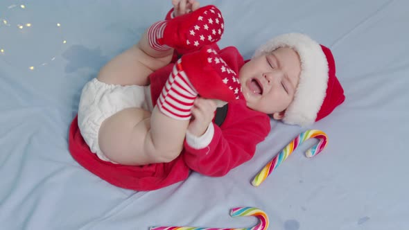 Christmas Portrait of Cute Crying Little Newborn Baby Girl Wearing Santa Hat alt