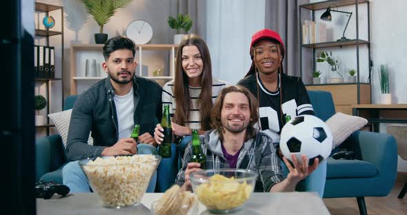 Mixed Race Friends Gathering Together at Home to Watch Sport Game on TV with Beer alt