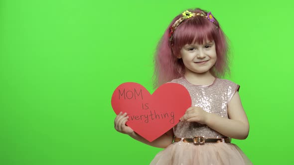 Child Girl Princess Holds Red Paper Heart with Text About Mother. Mother's Day alt