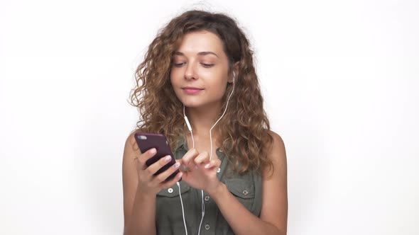 Portrait of Caucasian Female Music Lover Finding Favourite Tune in Smart Phone Smiling Listening It alt