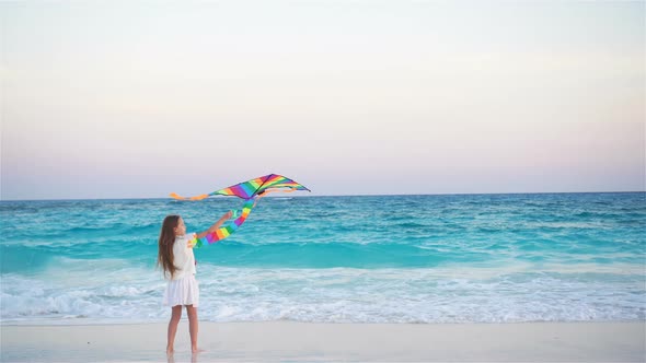 Little Girl with Flying Kite on Tropical Beach at Sunset. Kid Play on Ocean Shore. Child with Beach