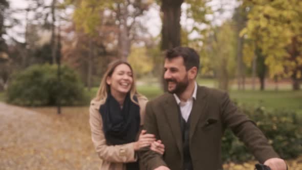 Handsome young couple in the autumn park with electrical bicycle