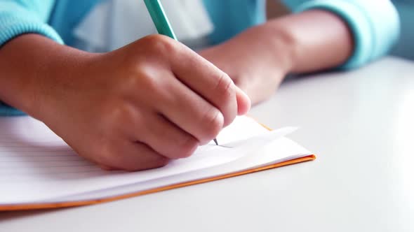Mid-section of school kid doing homework in classroom at school alt