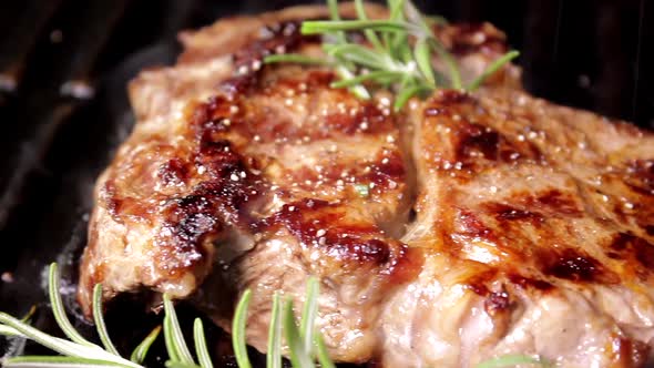 Grilling beaf steak. Cooking and pouring pepper on meat.  Delicious food preparation. alt