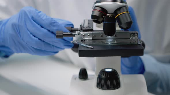 Close Up of Specialist Hands Using Microscope Tool alt