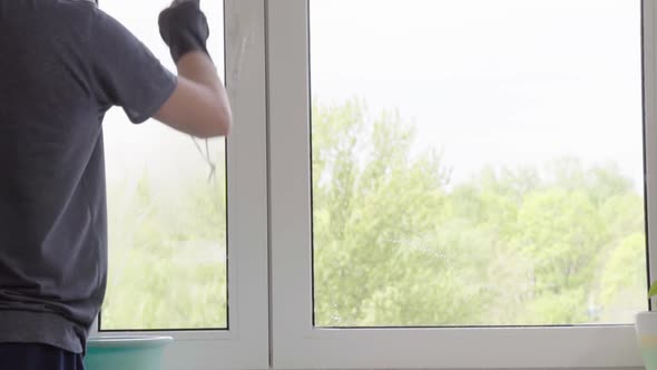 Man washes the windows with special foam and cleans them. Cleaning service. Worker in black gloves alt