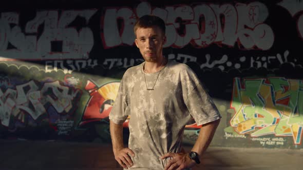 Handsome Man Relaxing After Training at Skate Park with Graffiti Wall alt