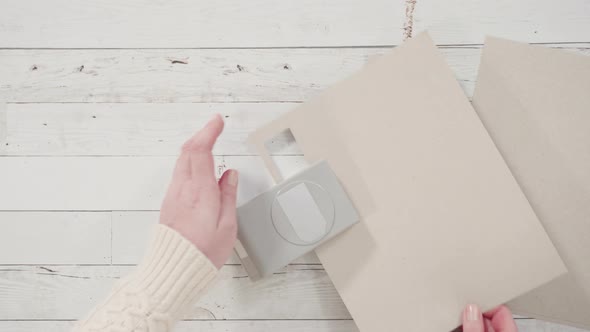 Flat lay. Step by step. Cutting out gift tags from brown paper with a paper punch. alt