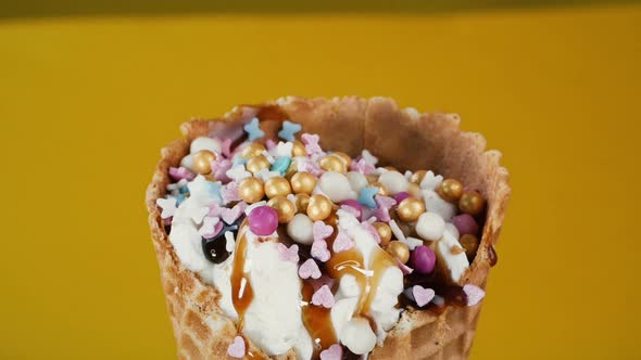Ice Cream Is Decorated with Multi-colored Pastry Sprinkles, Close-up. Vanilla Ice Cream Cone with