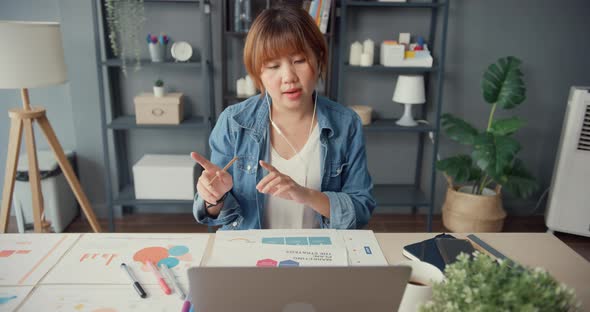 Asia businesswoman using tablet talk to colleagues about plan in video call while working from house alt