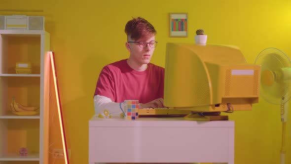 Young Man IT Specialist Is Working at Yellow Retro PC