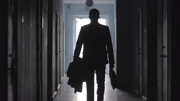 Rear View of Silhouette of Businessman Walking in Hallway