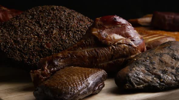 Rotating shot of a variety of delicious, premium smoked meats on a wooden cutting board  alt