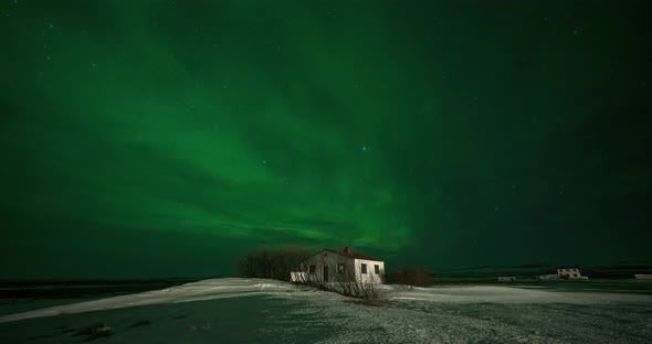 Timelapse of Aurora Borealis Northern Lights Over Small Building in the Show Field. Iceland in the