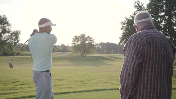 Handsome Middle Eastern Golfer Swinging and Hitting Golf Ball on Beautiful Course. An Older Man alt