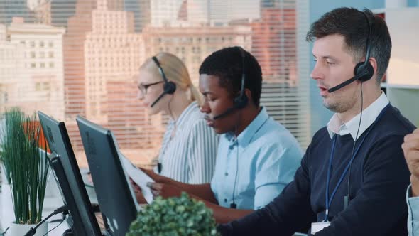 Customer Support Agent Receiving an Important Document From His Colleague While Talking with Client