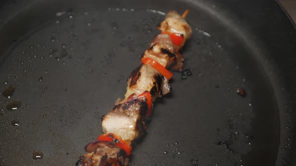 Meat and vegetable skewer cooked on a black pan in peanut oil. OVERHEAD SHOT. PULL BACK SHOT. alt