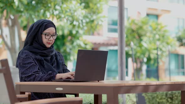 good looking Muslim women sitting outside working according to the slogan work form home alt