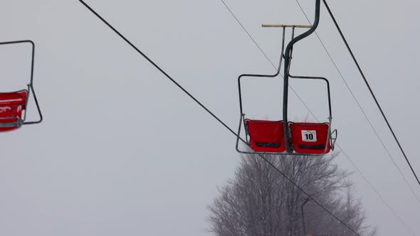 View of the Ski Lift Against the Background of a Mountain Forest and Gray Sky in the Carpathians alt