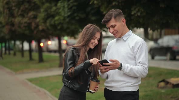 A Man is Showing a Photo on a Smartphone to a Young Woman alt