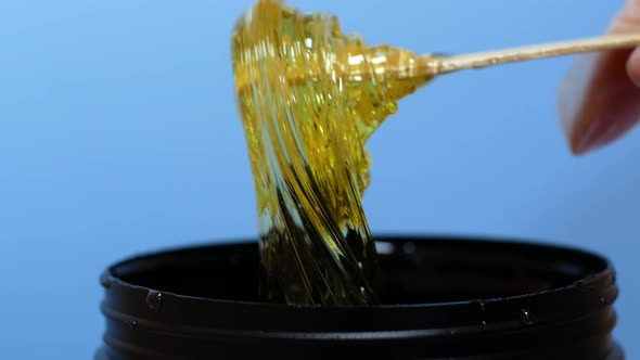 Sugar paste or honey wax for hair removal, dripping from wooden wax sticks - depilation and beauty alt