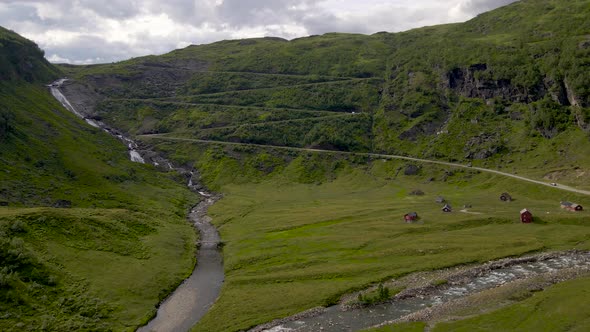Aerial view of car driving on a narrow mountain pass road. Scenic natural landscape with waterfall a alt