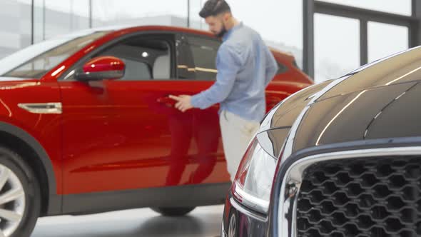 Young Handsome Man Examining Cars Sold at Automobile Dealership
